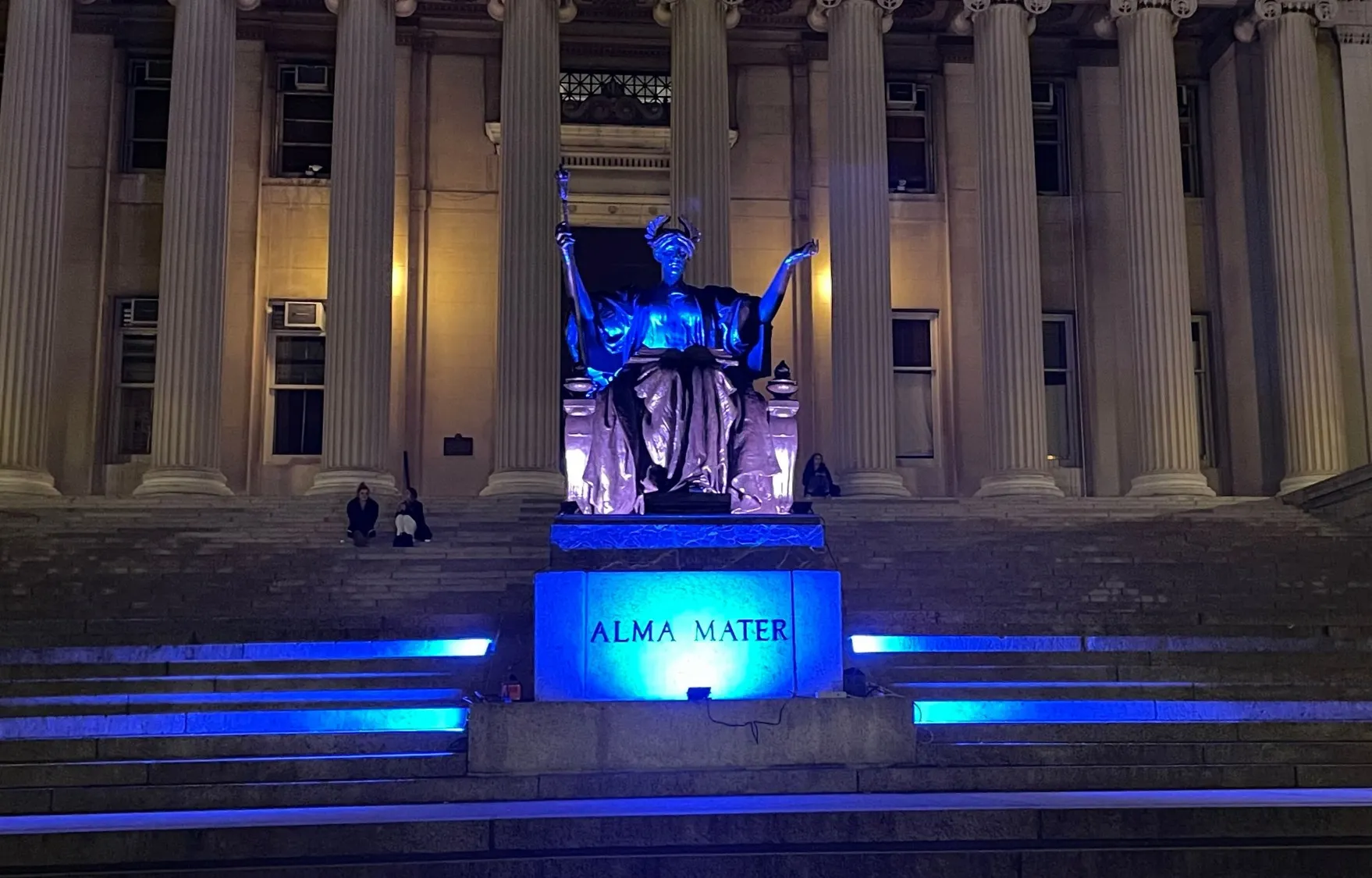 Alma Mater statue at Columbia University illuminated in blue light